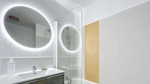 Une salle de bain moderne avec une douche à parois de verre, un meuble-lavabo blanc avec un miroir et une baignoire.