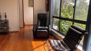 A spacious room with a large window, a leather chair, and a wooden floor.