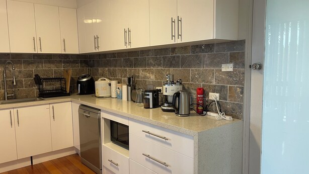 A modern kitchen with white cabinets, a granite countertop, and a stainless steel dishwasher.