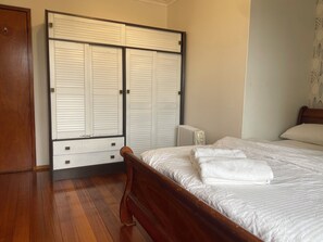 Un dormitorio con una cama de madera, un radiador blanco y un armario con puertas correderas.