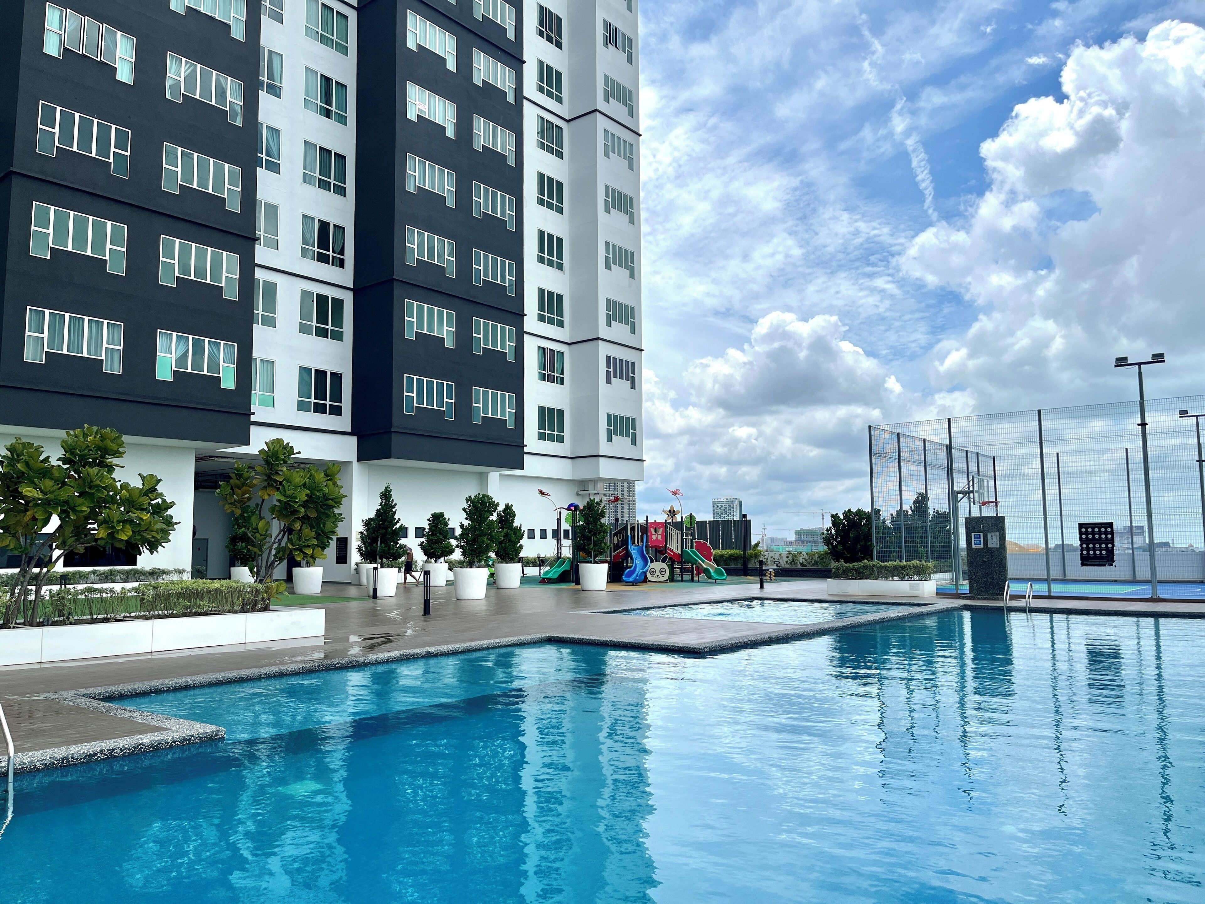 A modern building with a swimming pool, playground, and landscaped area.