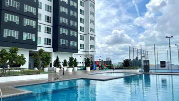 A modern building with a swimming pool, playground, and landscaped area.