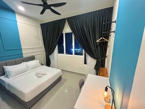 A modern hotel room with a bed, a desk, a ceiling fan, and a window with curtains. - Amber Cove Melaka by Manhattan Group (Malacca City)