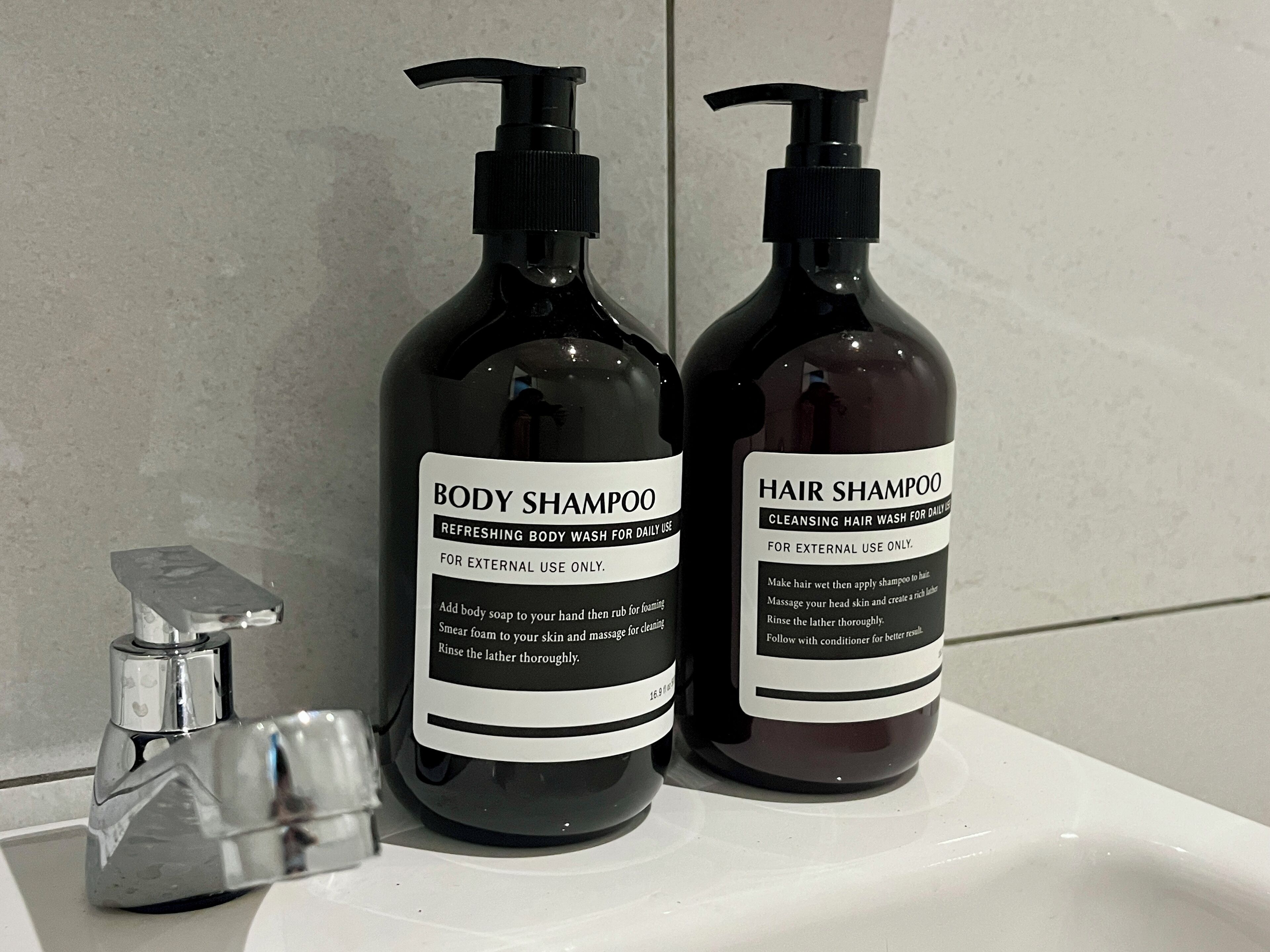 Two bottles of body and hair shampoo on a bathroom sink.
