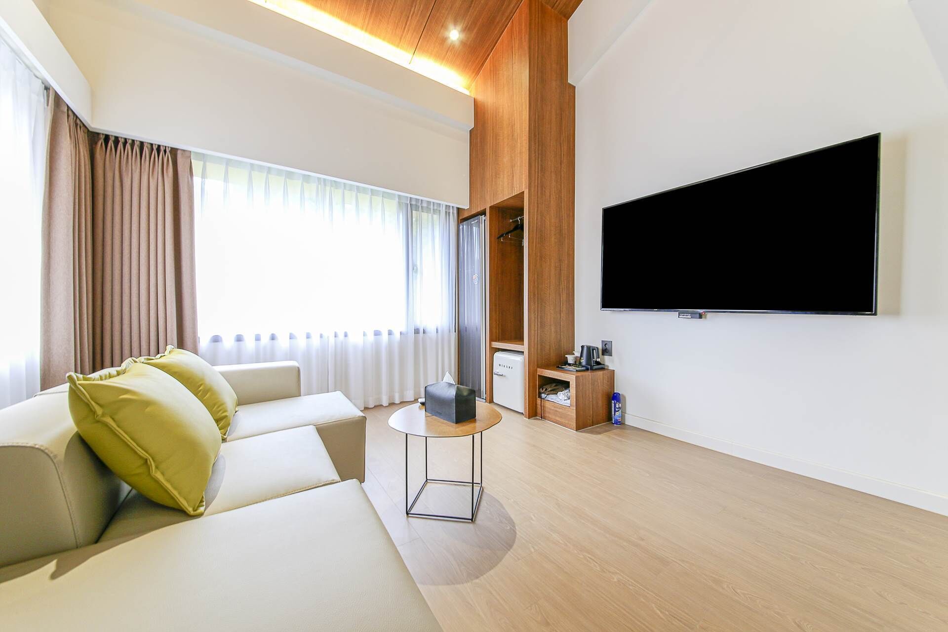 A modern living room with a sofa, a coffee table, a TV, and a mini-fridge.