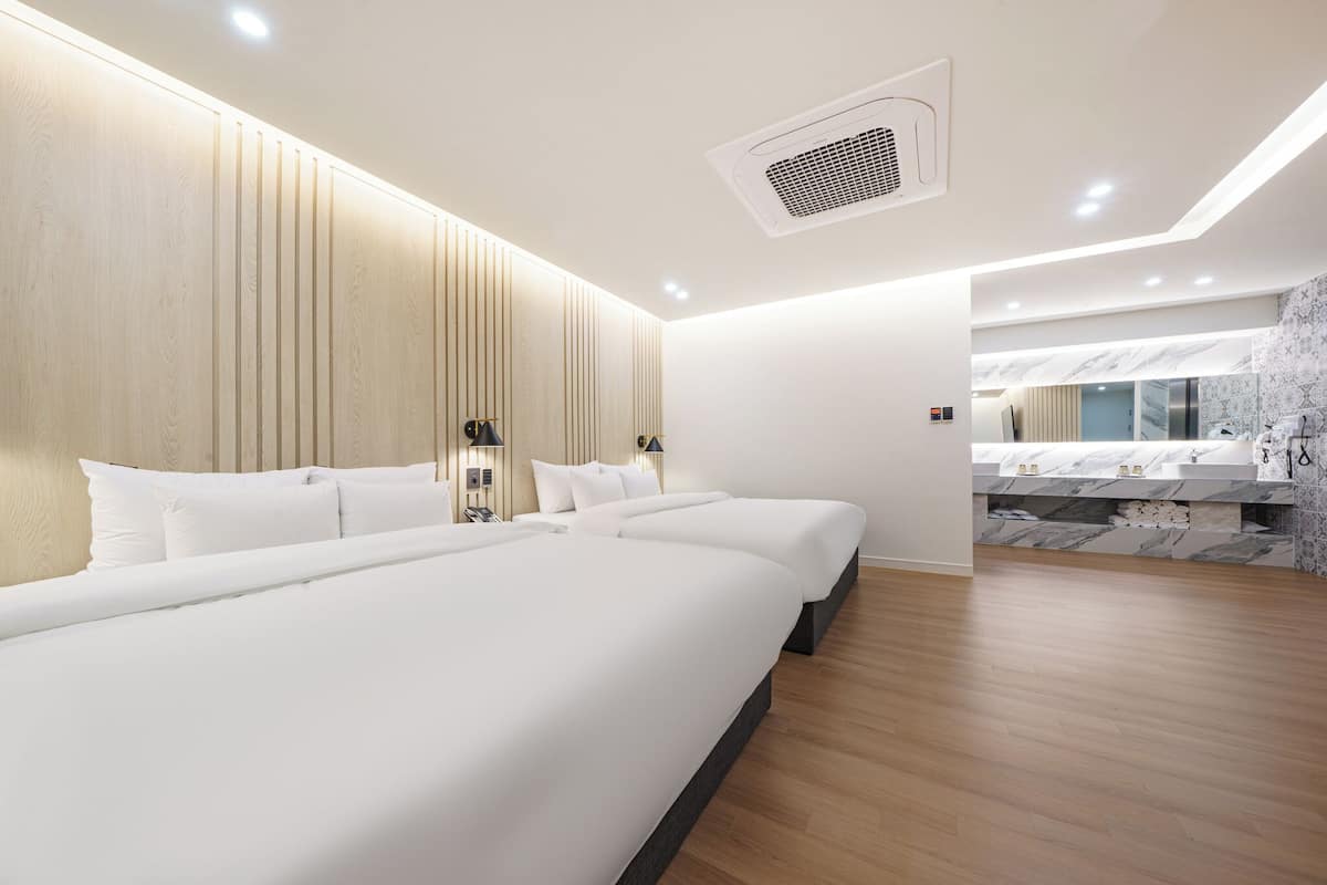 Ein modernes Hotelzimmer mit einem großen Bett, einem Nachttisch, einem Spiegel und einem Badezimmer mit Marmorplatte.
