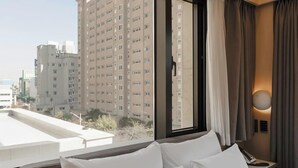 A hotel room with a large window, a bed, a bedside table, and a view of high-rise buildings. - Browndot Hotel Mokpo Gotbawi (Mokpo)