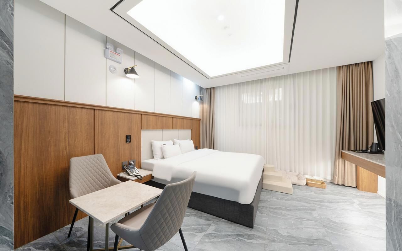 Una habitación de hotel con cama, escritorio, silla, televisor y tragaluz.