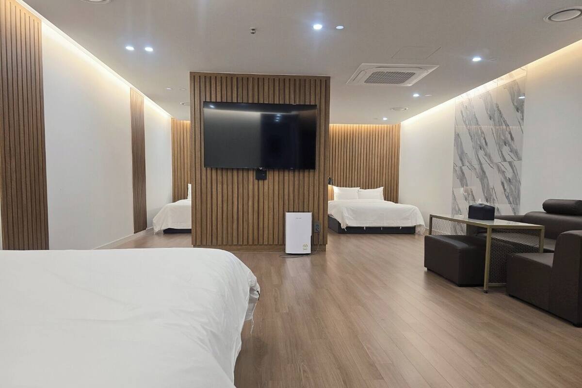 Ein modernes Hotelzimmer mit zwei Betten, einem Flachbildfernseher, einem kleinen Tisch und einer Wand mit Marmorverkleidung.