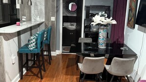 A modern kitchen with a marble countertop, a sink, and a dining area with a black table and chairs. - Spacious DC Getaway • Modern Comfort • Walk-In Shower • Near Metro (Washington)