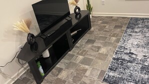 A black entertainment unit with a flat-screen TV, a remote control, and decorative items. - 3-bedroom townhome with AC (Indianapolis)