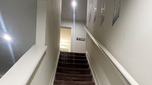 A carpeted staircase with a handrail, a 'No Smoking' sign, and a light fixture at the top. - 3-bedroom townhome with AC (Indianapolis)