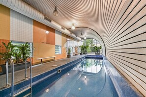Relax by the pool surrounded by lush greenery and a unique ceiling design.