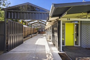 Guests can access their room through the door marked 24, situated in a covered outdoor area with a pathway.