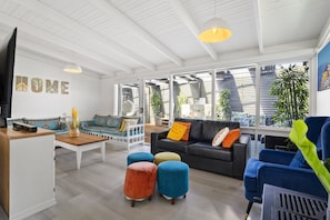 Relax in this spacious living room with a large window, black leather sofa, and colorful seating.