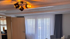 A modern living room with a dark grey sofa, a fluffy white throw, and a wooden dining table with chairs. - Time out at the mountain spring with 2 bedrooms, bathroom with shower/WC and terrace (Schönau am Königssee)