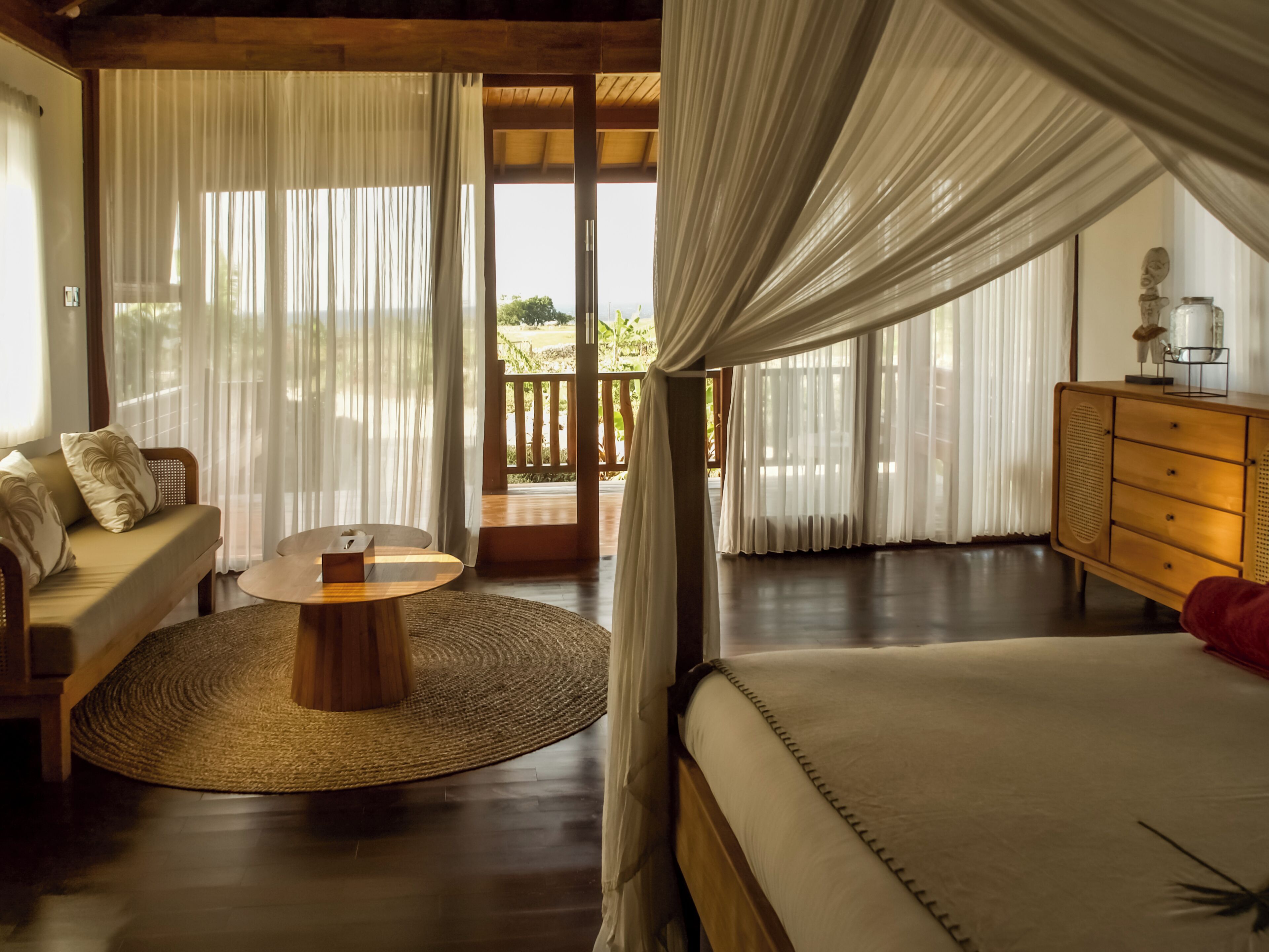 A room with a bed, a sofa, a wooden coffee table, and a dresser.