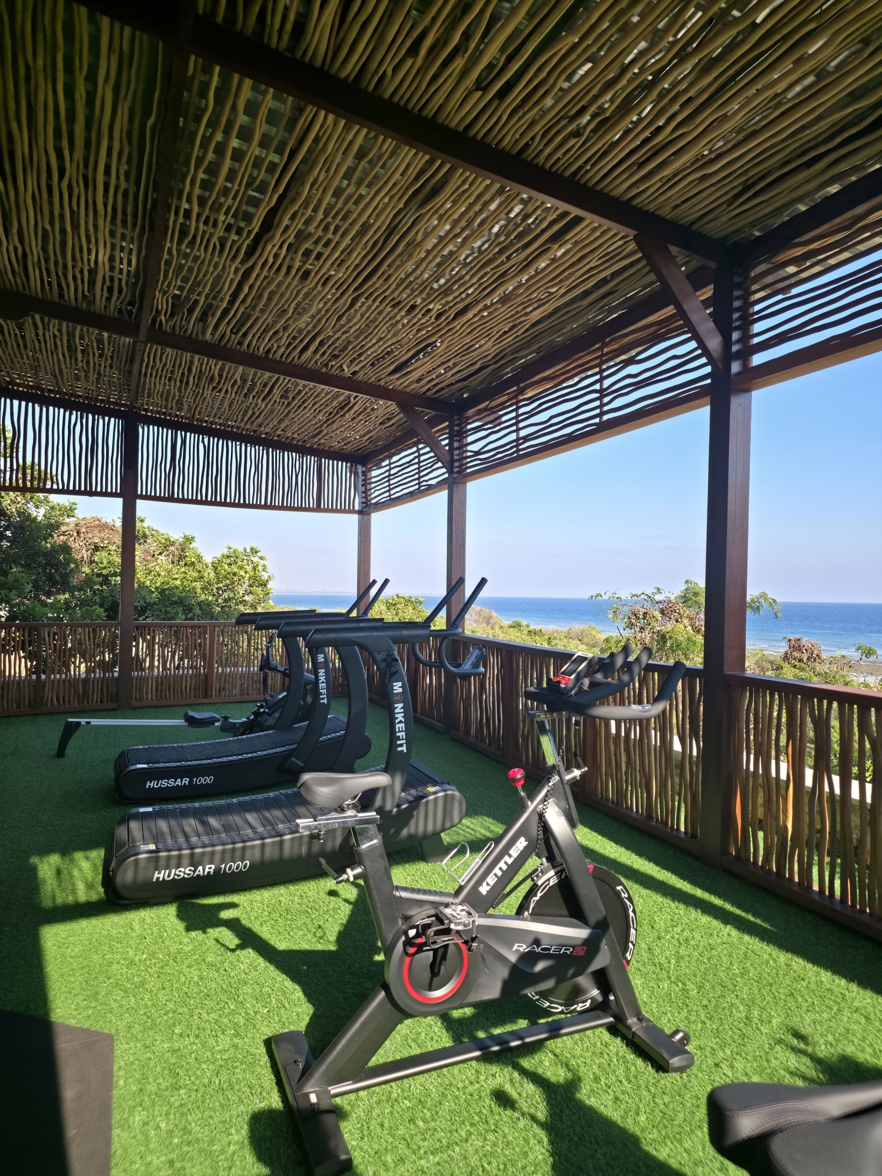 An outdoor gym with exercise equipment, a wooden deck, and a view of the ocean.