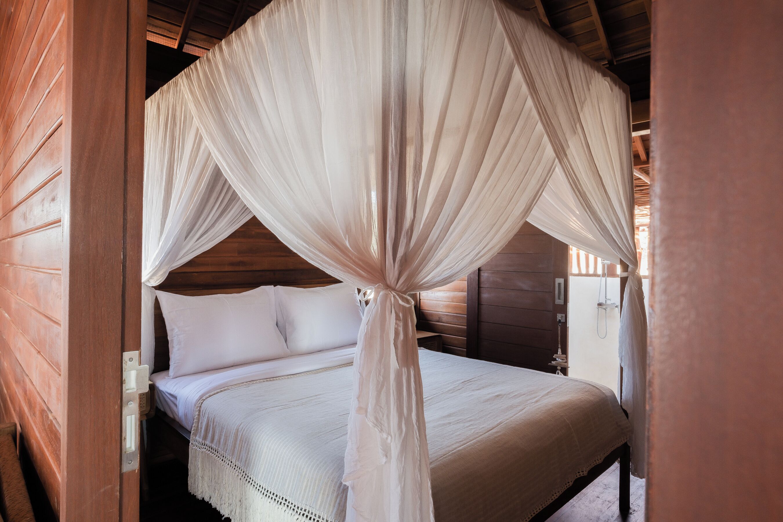 A bed with a canopy, wooden walls, and a nightstand with a lamp.