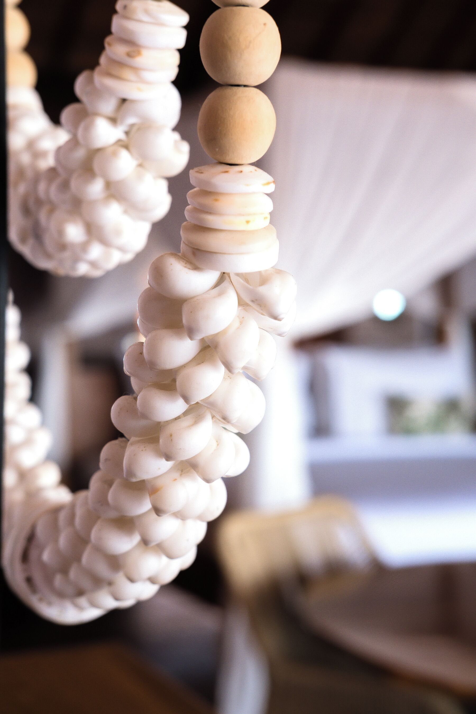 A close-up of a white, textured wall with a wooden bead hanging from it.