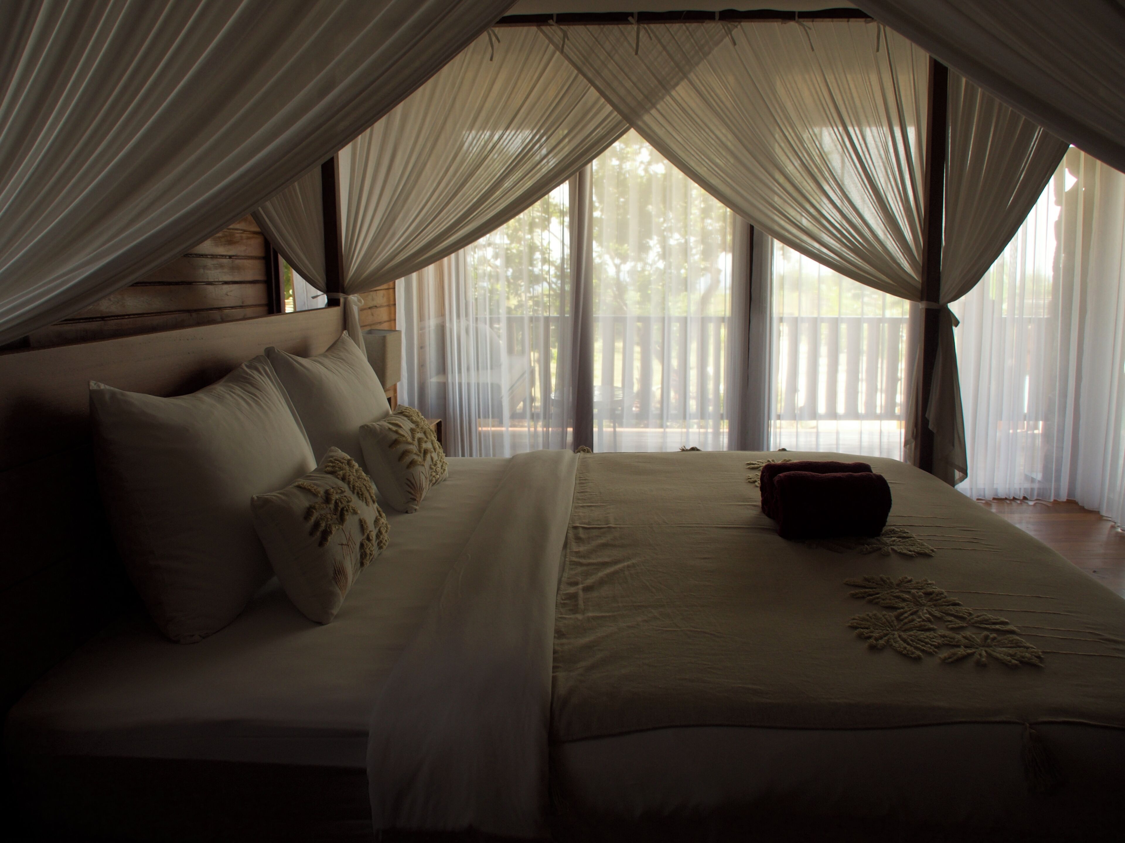 A bed with a canopy, pillows, and a bedside table.