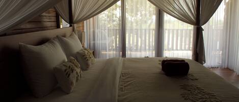 A bed with a canopy, pillows, and a bedside table.