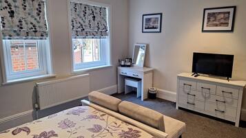 Cozy retreat with a bed, desk, and TV, perfect for relaxation and work.