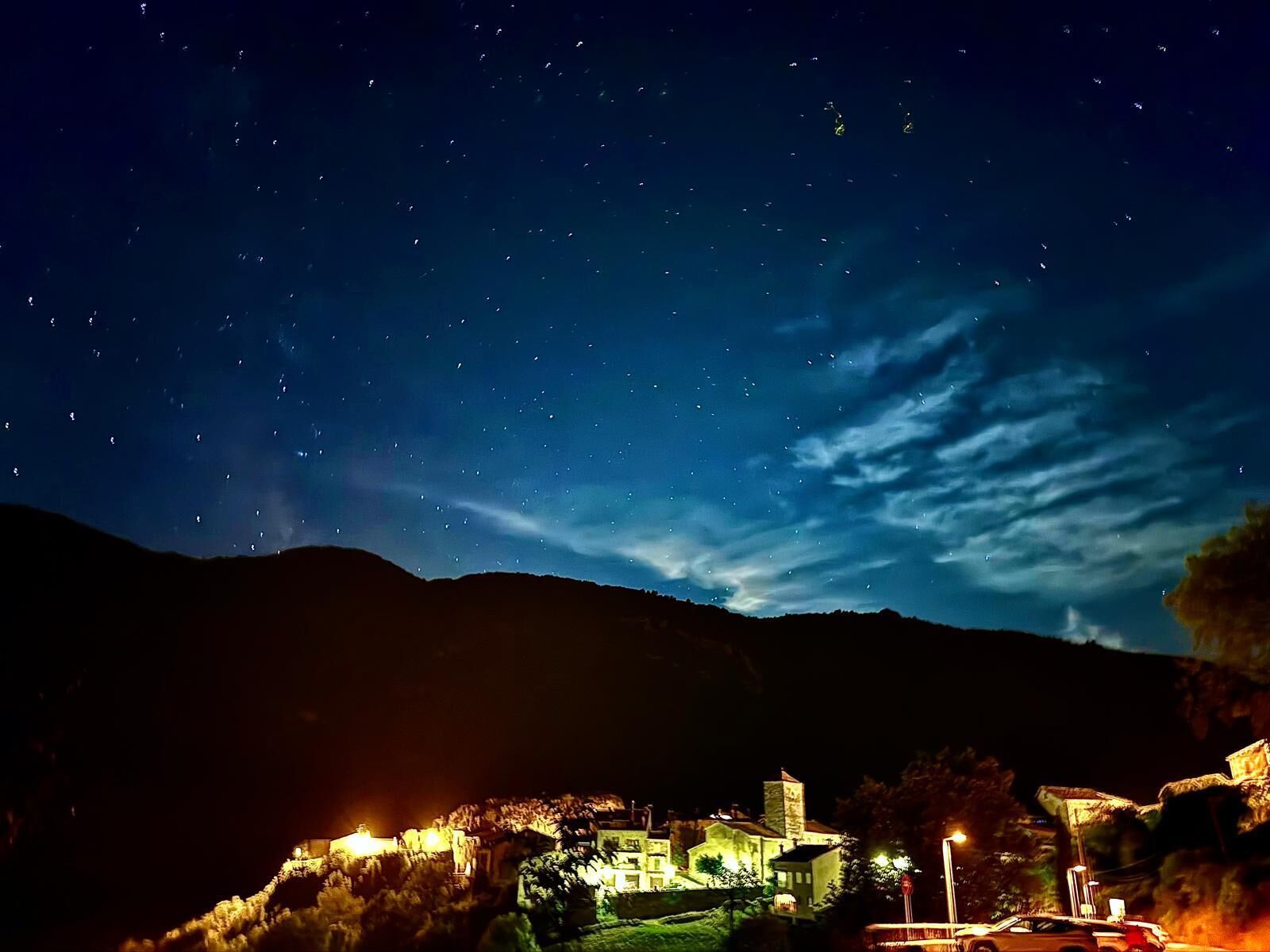 Un bâtiment historique aux fenêtres illuminées et doté d’une tour imposante, se dressant sur fond de ciel étoilé.