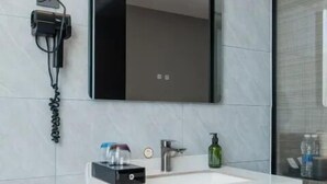 A modern bathroom with a white sink, a mirror, a towel rack, and a wall-mounted phone. - Wodeexas College West Road Branch (Dezhou)