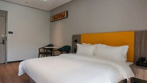 A hotel room with a large bed, a small table, two chairs, and a wooden nightstand. - Wodeexas College West Road Branch (Dezhou)