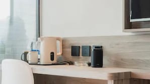 A modern kitchen with a wooden countertop, a white chair, a coffee maker, and a kettle. - Wodeexas College West Road Branch (Dezhou)