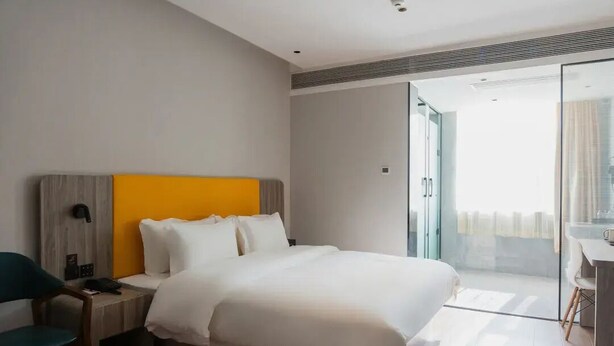 A modern hotel room with a large bed, a desk, and a chair. - Wodeexas College West Road Branch (Dezhou)