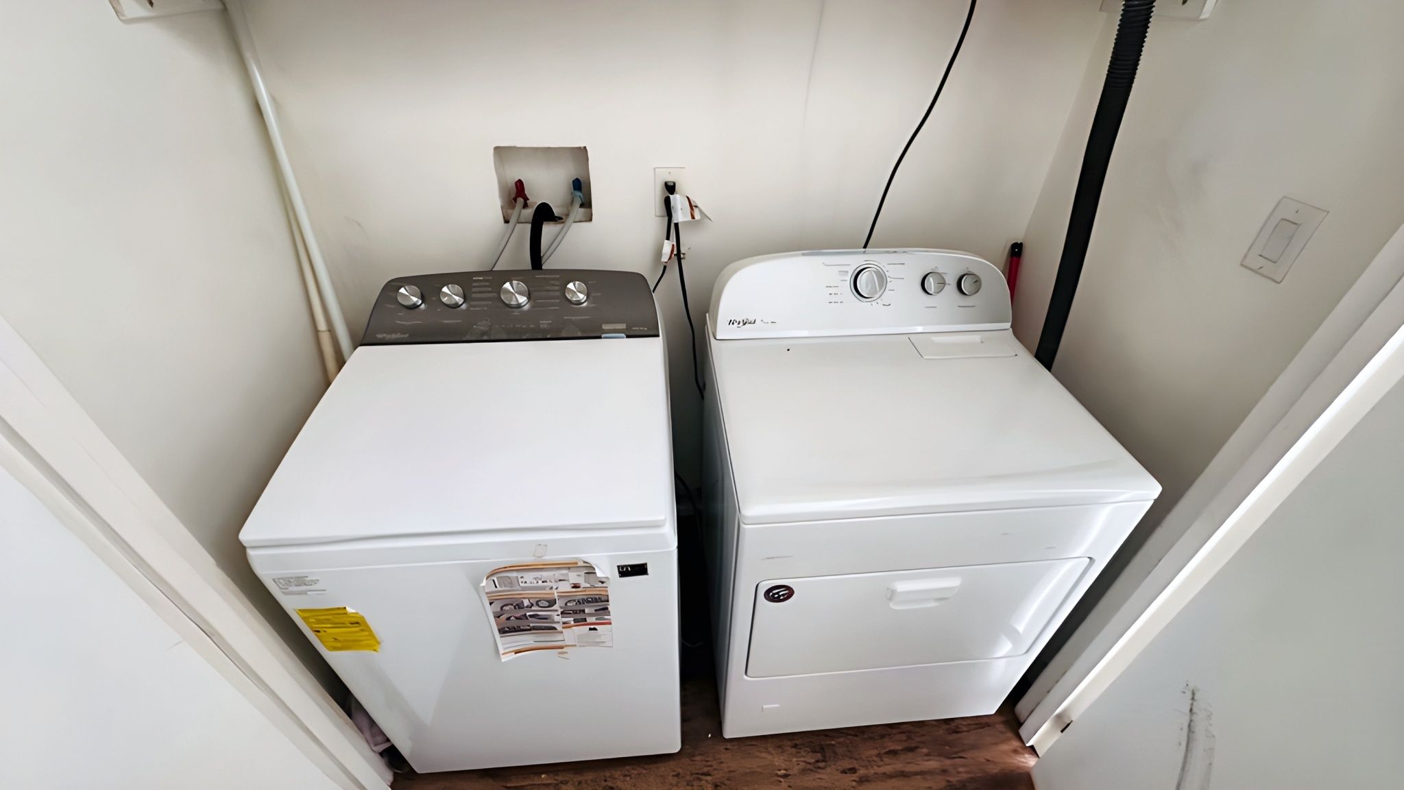 Une buanderie équipée de deux machines à laver et deux sèche-linge superposés, d’une prise de courant et d’une prise électrique murale.