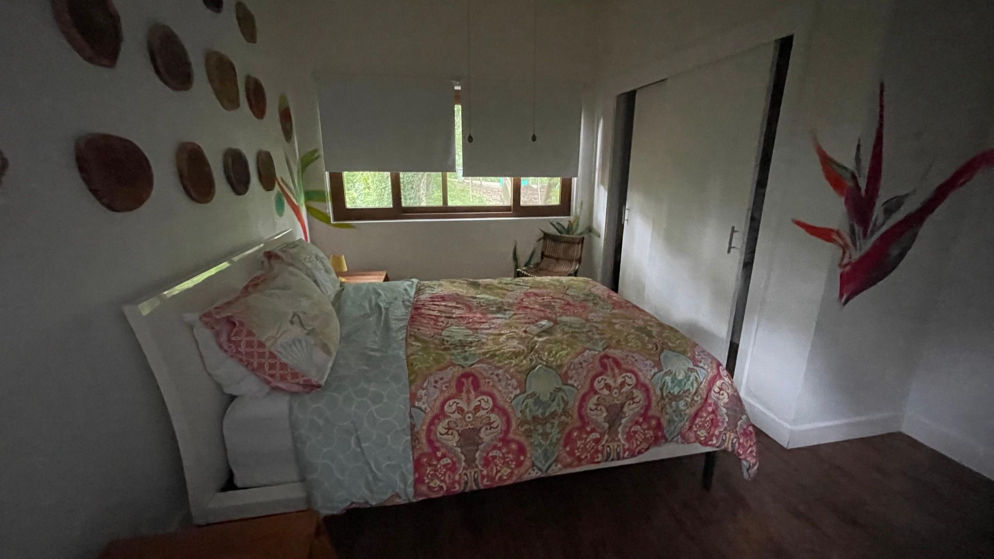 A bedroom with a bed, a window, a chair, and a wall with circular decorations.