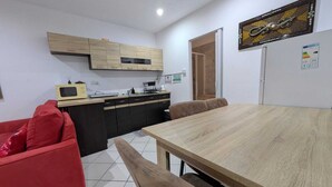 A compact living space with a kitchenette, a dining area, and a red sofa. - Valletta Cosy Apartment (Il-Belt Valletta)
