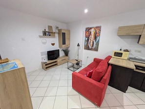 Una sala de estar con un sofá rojo, mueble de entretenimiento de madera y un cuadro en la pared.