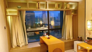 A hotel room with a large window, a wooden desk, and a small table. - Yuan Culture Hotel Shenzhen (Shenzhen)