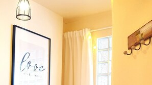 A bedroom with a bed, a framed inspirational quote, a hanging light fixture, a window with curtains, and a wooden chair. - Happy Ocean - ground floor apartment: vacation with family & dog, 2 min. to the beach. (Pobierowo)