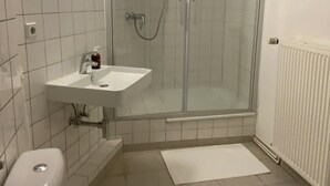 A bathroom with a toilet, sink, and glass-enclosed shower.