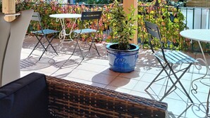 A covered patio area with a wooden ceiling, outdoor furniture, and a potted plant. - Gite la Rose des Alpes (Serres)