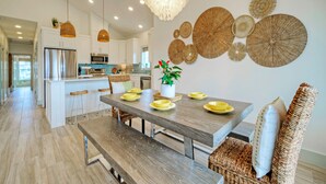 Una cocina moderna con armarios blancos, electrodomésticos de acero inoxidable y una isla central con taburetes de bar.