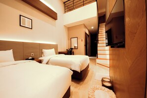Une chambre d’hôtel avec deux lits, une télévision et un escalier menant à un étage supérieur.