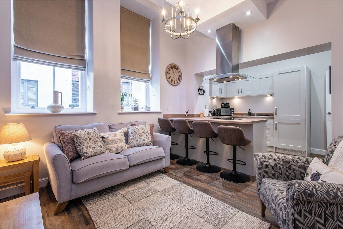 A modern living room with a sofa, a coffee table, a rug, and a bar area with stools.