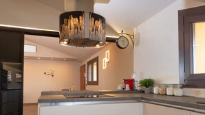 Una cocina moderna con una isla central, iluminación colgante y un reloj en la pared.