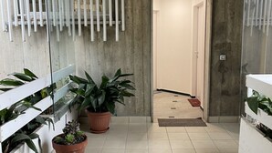 A hallway with potted plants, a tiled floor, and a door leading to another room. - Bnbook Residenza Balzarotti 1 (RHO)