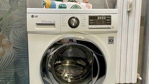 A front-loading LG Direct Drive 6kg washer with a digital display, placed in a bathroom with a tiled wall and a radiator. - Bnbook Residenza Balzarotti 1 (RHO)