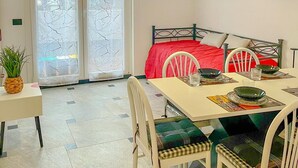 A room with a dining table set for four, a bed with a red bedspread, and two pendant lights above the table. - Bnbook Residenza Balzarotti 1 (RHO)