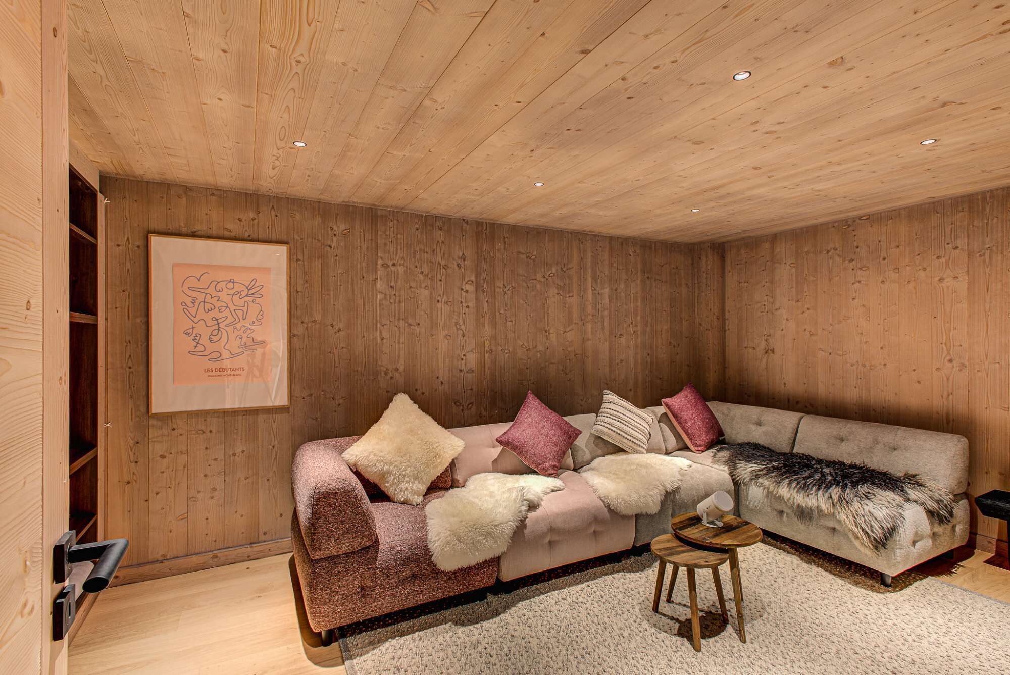 Una habitación acogedora con paredes y techo de madera, un sofá con cojines mullidos y una obra enmarcada en la pared.