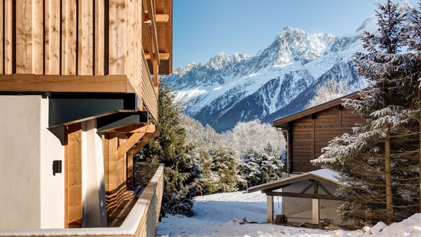 Una cabaña de madera con vistas a montañas nevadas.