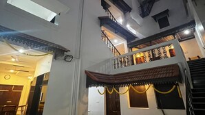 A multi-story building with a central courtyard, a staircase, and a dining area with chairs and tables. - Villa Vedapuri (Puducherry)